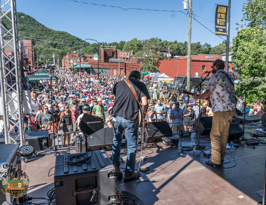Two musicians on stage with a large crowd enjoying the show. It's Boonerang in Downtown Boone, NC. Depot Street Stage in 1923.