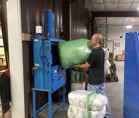 Anemployee loading the plastic bailer at Mast Store headquarters