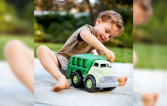 Young child playing with a toy garbage truck