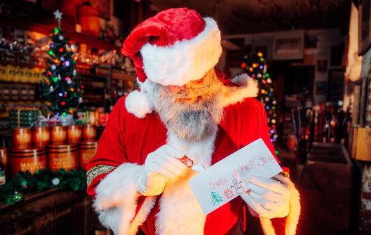 Santa opens a letter from a child inside a candlellit Mast Store