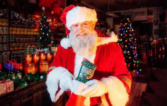 Santa holding a pair of Mast Store socks inside the Mast Store.