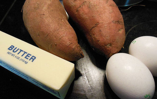 Ingredients of a sweet potato pie including butter, sweet potatoes and eggs.