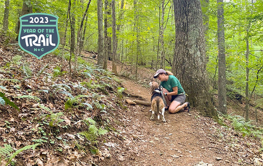 Woman hiking with a dog along a mountain trail.