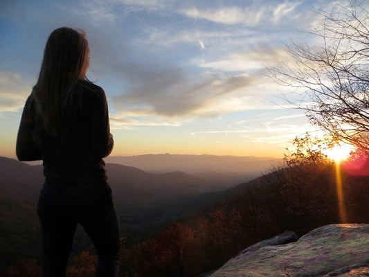 Woman standing on rock at sunset