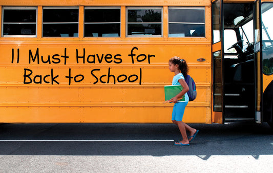 Child wearing a bookbag walking beside a school bus.