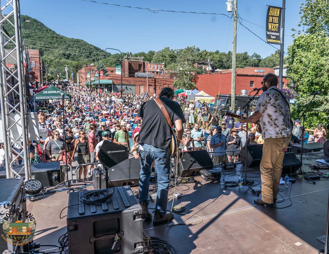 Two musicians on stage with a large crowd enjoying the show. It's Boonerang in Downtown Boone, NC. Depot Street Stage in 1923.