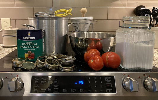 Canning equipment and tomatoes on top of a stove