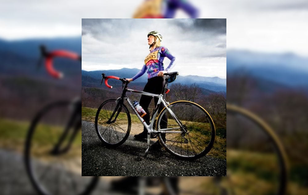 Kimberly Masters standing beside her bike on a mountaintop