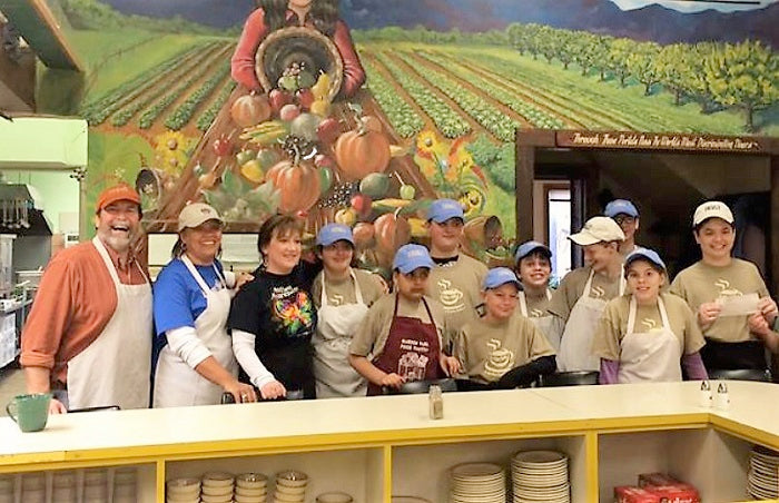 FARM Cafe staff behind a serving counter in front of a farmland mural