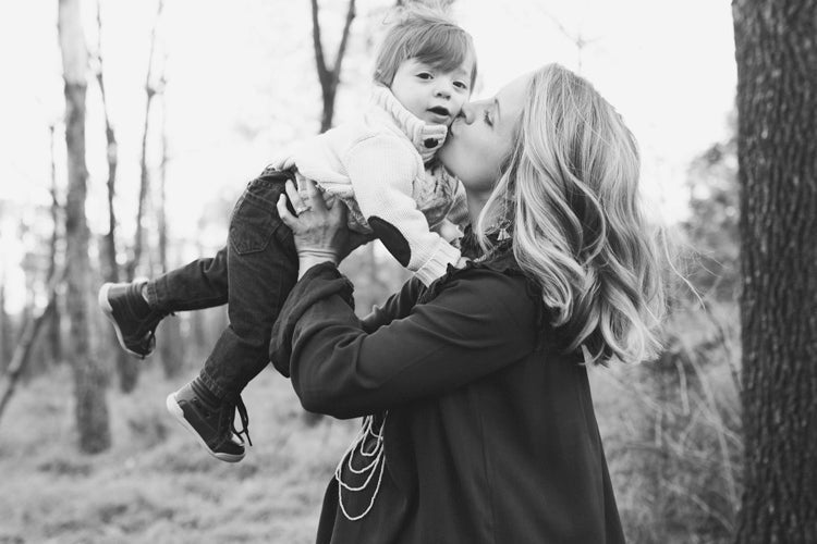 Woman kissing child that she is holding above her
