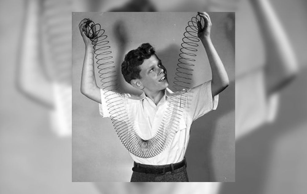 A child playing with a Slinky circa 1950s