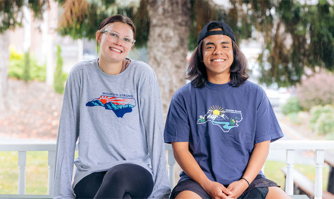 A woman and a man stitting on a porch wearing Mountain Strong T-shirts