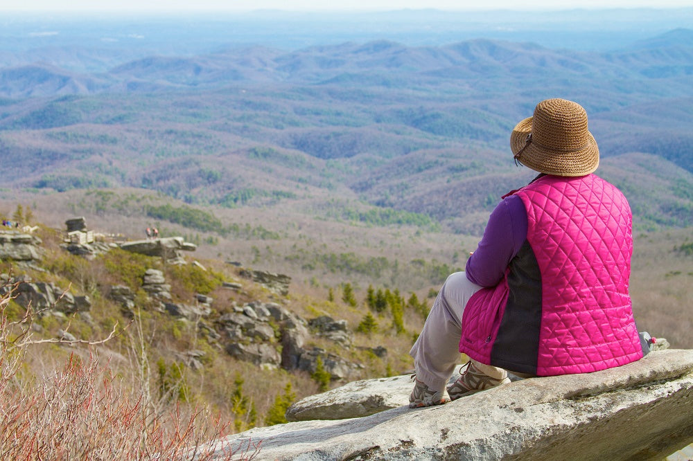 A woman sitting on a rock overlooking the Blue Ridge