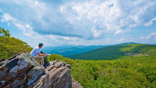 A hiker sitting on a rock overlooking the Shenandoah Valley