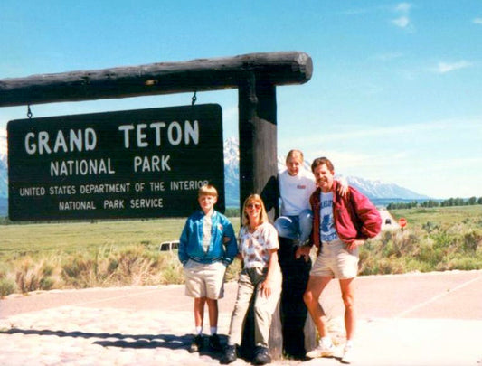 A family standing next to the Grand Teton National Park Sign