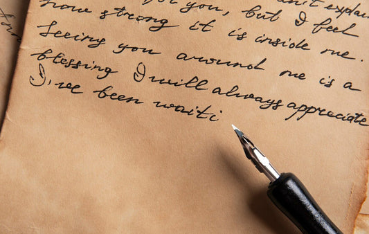 A sheet of paper with cursive writing and and old-fashion pen.