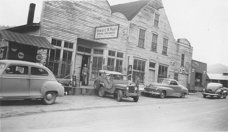 Black and white photo of the Mast Store in the 1940s with cars and a Jeep parked out front