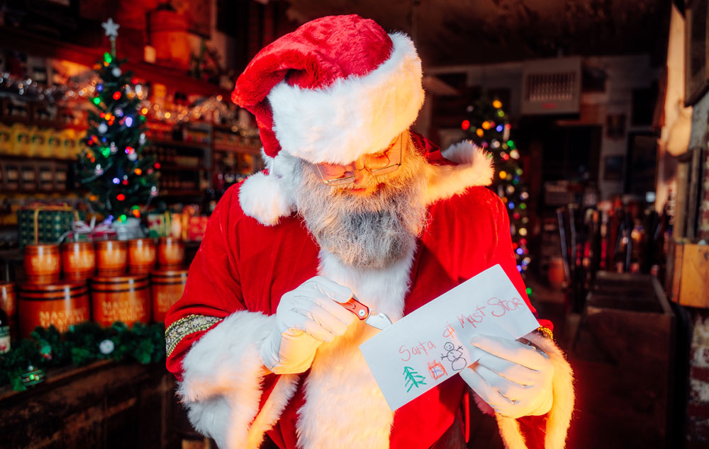 Santa opens a letter from a child inside a candlellit Mast Store