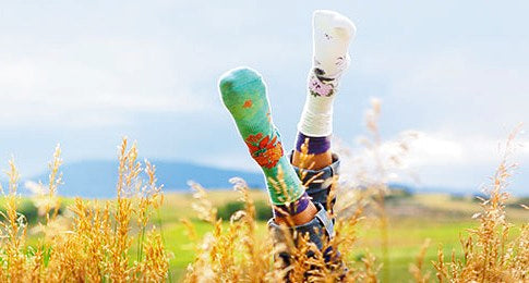 Someone on their back in a field wearing Smartwool Socks with their feet in the air