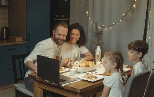 A family enjoying a socially-distant Thanksgiving meal with a computer on the table.