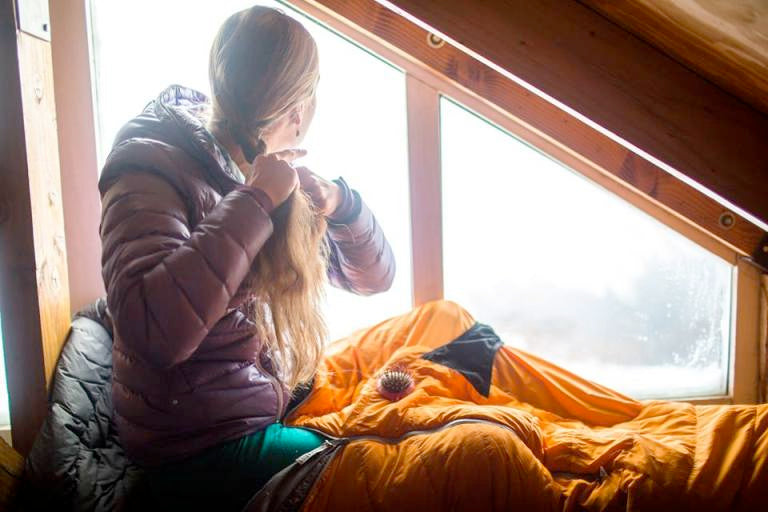 Woman in a seeping bag sittin on a Therm-a-Rest