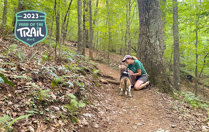 Woman hiking with a dog along a mountain trail.