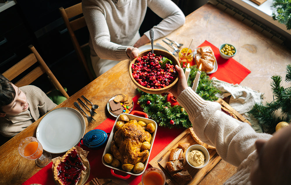 A Festive Holiday Table Full of Family Dishes being passed around