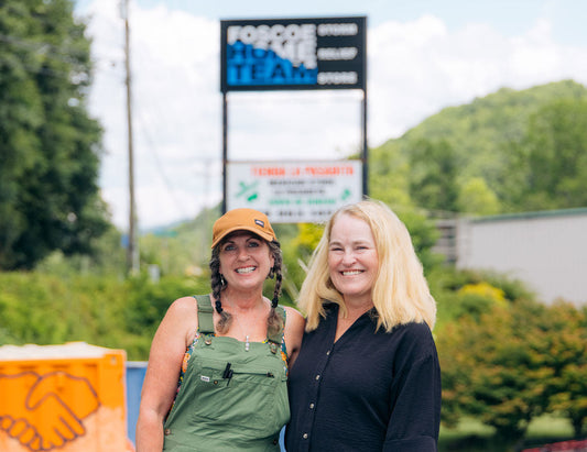 Two women standing in front of a blurry background. Left Sherrye Trice of Foscoe Home Team and right Lisa Cooper, president of Mast General Store.