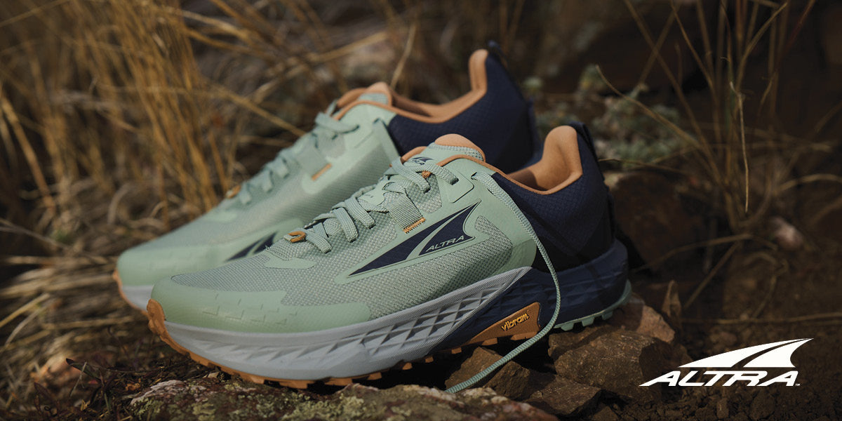 A pair of Altra running shoes on a rocky surface.