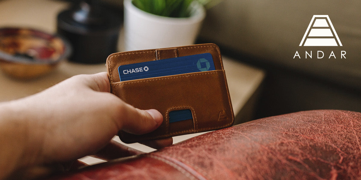 Person holding an Andar brown leather wallet with a credit card.