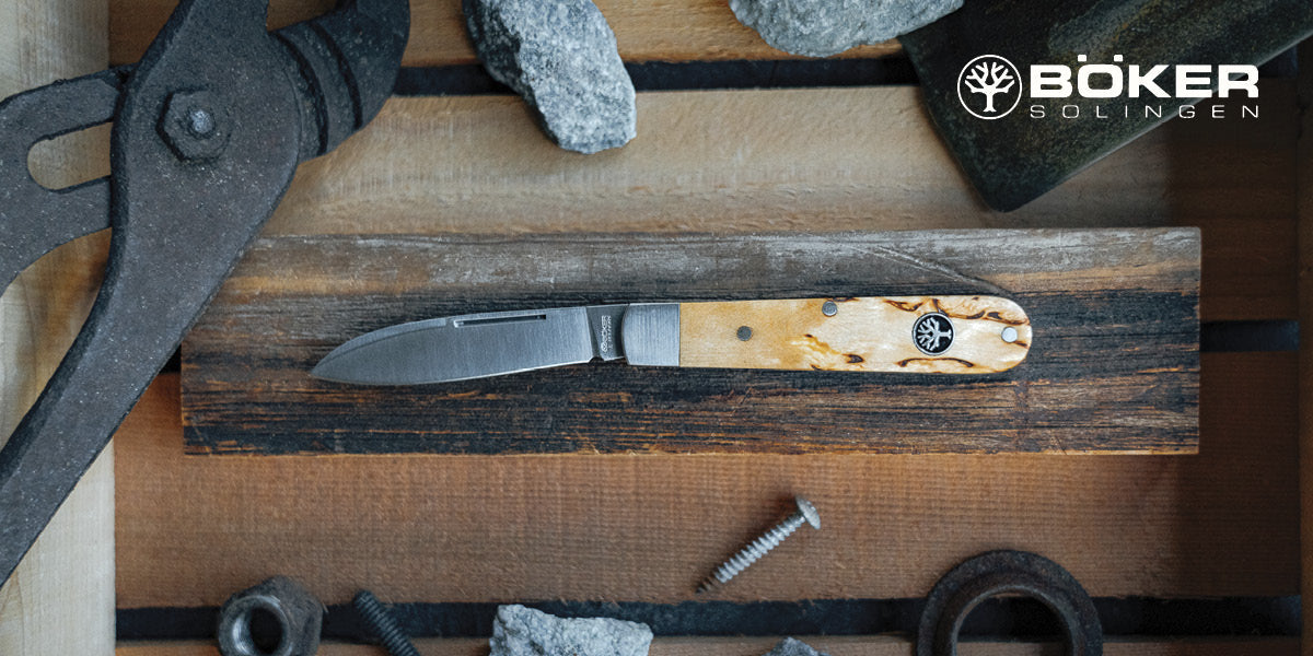 Boker knife with wooden handle on a wooden surface with tools around