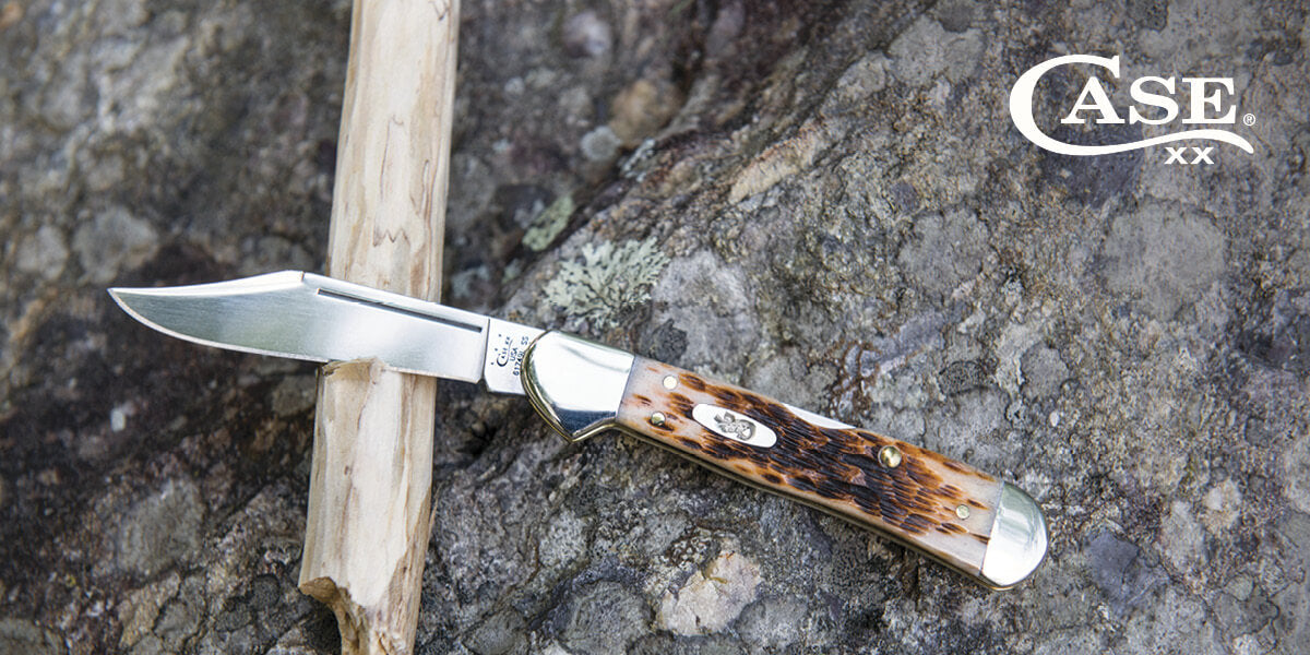 Case knife with brown handle on a rocky background.