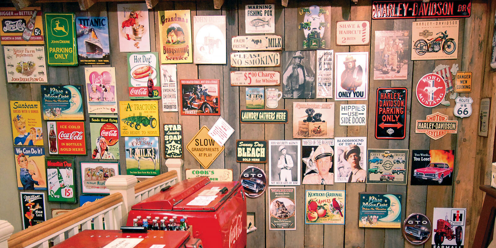 A collection of vintage metal signs displayed on a wooden wall at the Mast General Store in Knoxville, TN