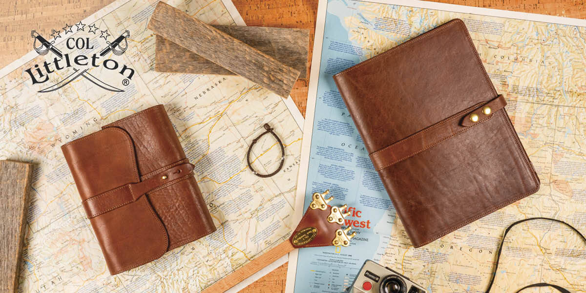 Two Colonel Littleton brown leather notebooks and a back scratcher arranged on vintage maps.