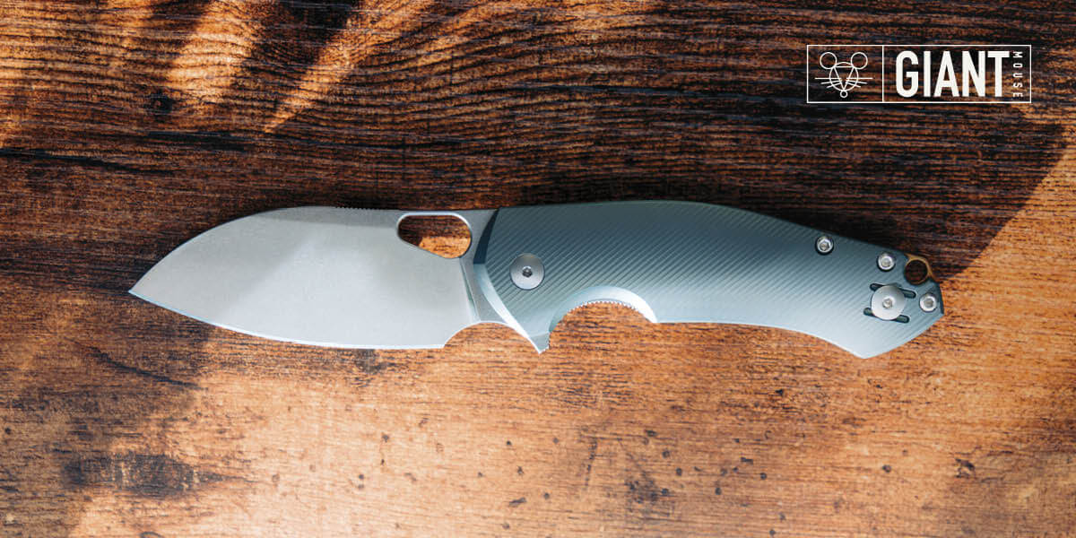 A Giant Mouse folding knife on a wooden surface.