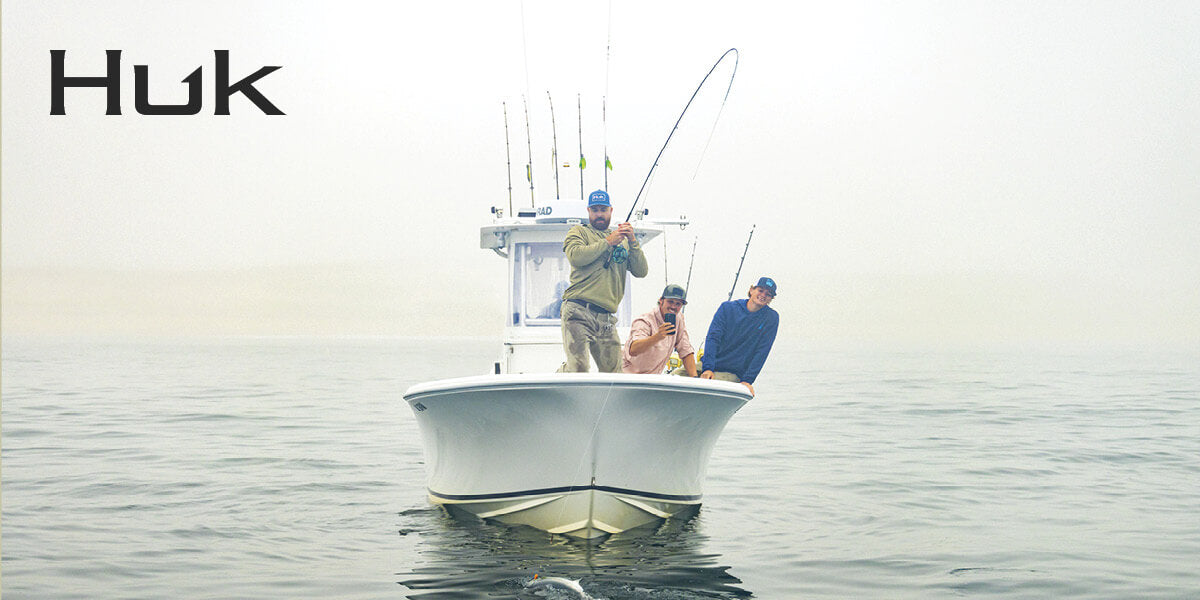 Three men wearing Huk performance hoodies fishing on a boat.