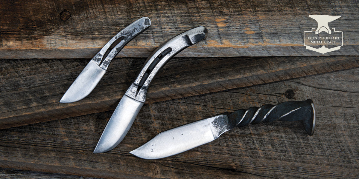 Three Iron Mountain Metal Craft knives on a wooden surface.
