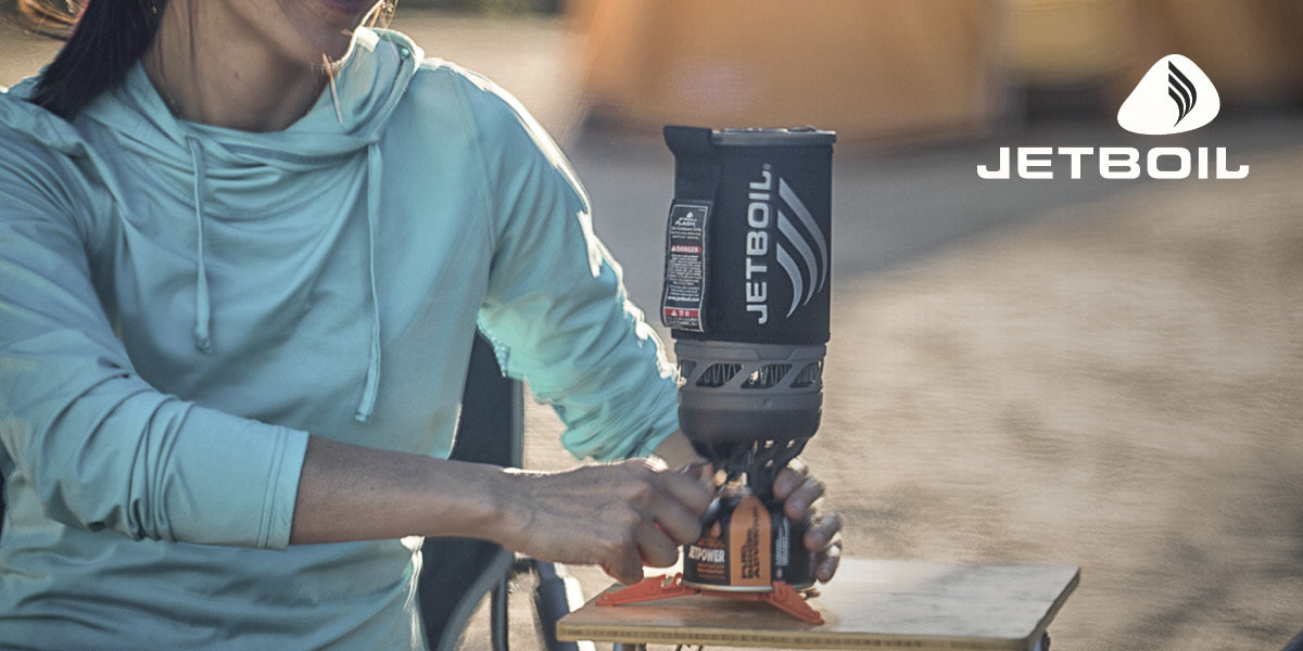 Person using a Jetboil camping stove outdoors.
