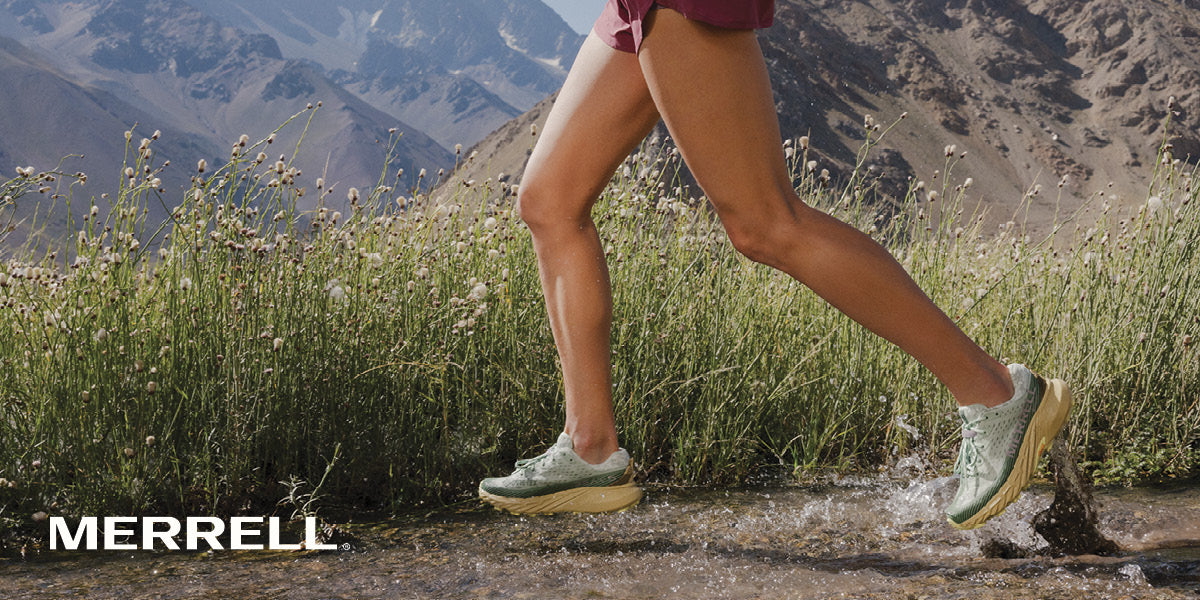 Person running on a mountain trail wearing Merrell shoes