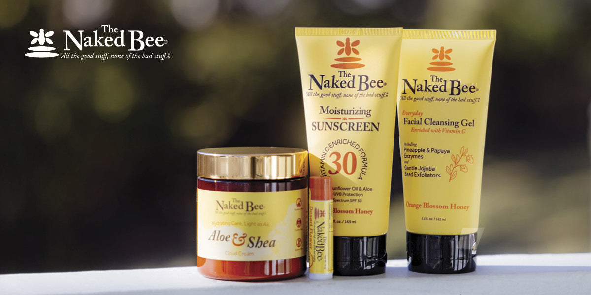 Naked Bee skincare products on a blurred natural background.