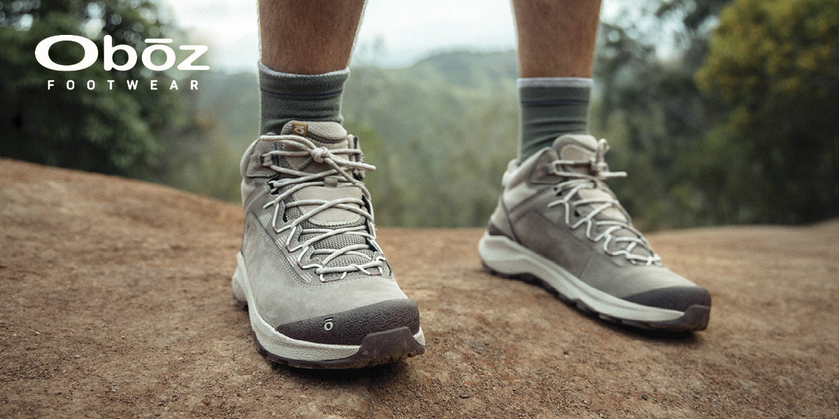 Person wearing gray Obōz hiking shoes on a natural outdoor trail.