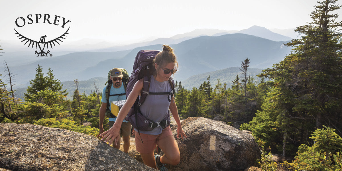 Two people hiking a mountain trail with Osprey backpacks.