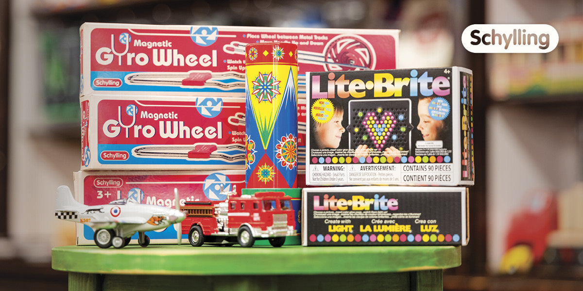 Classic Schylling toys like Gyro Wheels and Lite‑Brite set on a green stool in the store.