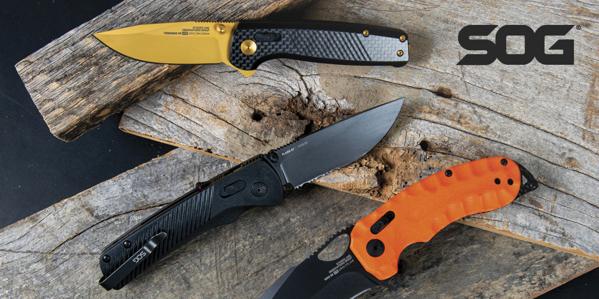 Three SOG folding knives with different colored handles on a wooden surface.