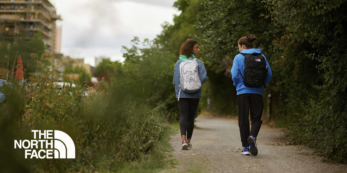 Two people walking along a path with The North Face backpacks.