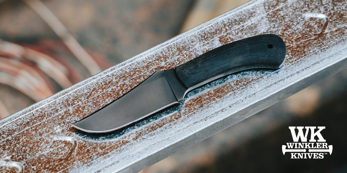 Winkler Knife with a black handle on a metal surface.