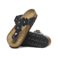 Black floral sandals with cork footbed and textured rubber sole, featuring decorative flower details and adjustable strap for comfort and style.