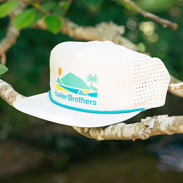 Aperture Tech Strapback Hat with the Howler Brothers logo on a branch against a natural background