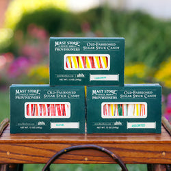 Three boxes of colorful Mast Store Provisioners Old-Fashioned Sugar Stick Candy on a wooden table