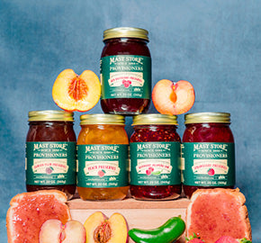 Mast Store Provisioners Jams, Jellies, Butters, and Spreads on a blue background with fruit. 
